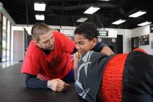 Brazilian Jiu Jitsu coach giving instruction to young practitioner. 