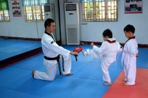 A young kid performing a karate front kick in martial arts for kids.