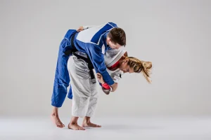 2 teenagers practicing judo which shows a hip lift being executed.